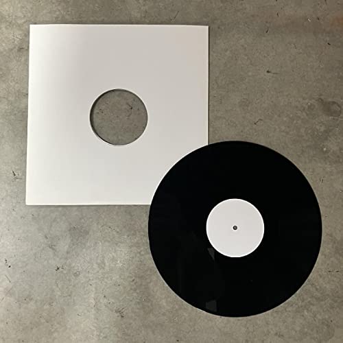 Black vinyl record and white inner sleeve lying on a gray surface.