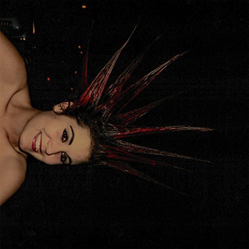 Person with dramatically spiked, red-streaked hair lying against a dark background.