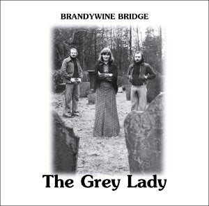 Black and white album cover featuring three people standing in a forest clearing.