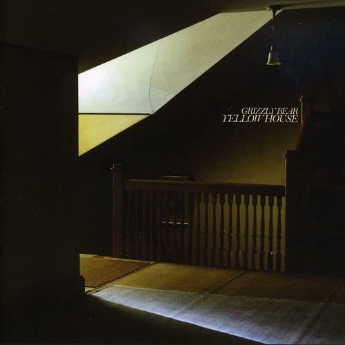 Dimly lit interior showing a wooden staircase railing and a sloped ceiling.