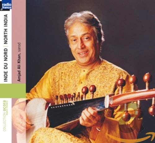 Amjad Ali Khan wearing a gold tunic, holding a sarod against a dark background.