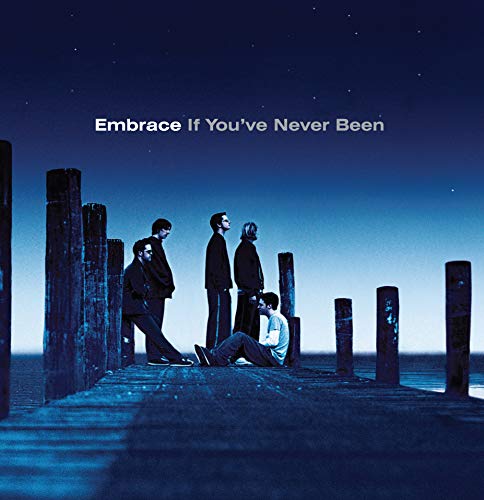 "Album cover with four men standing and sitting on a dock at dusk."