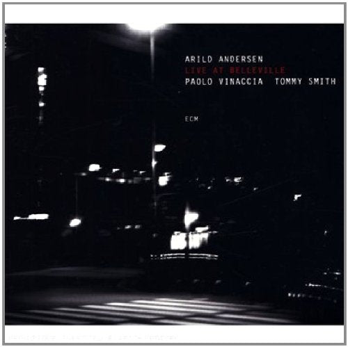 "Album cover with black and white cityscape at night and white and red text."