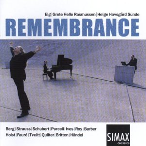 Man in black stands before seated pianist and conductor, arms raised, on a grey surface.