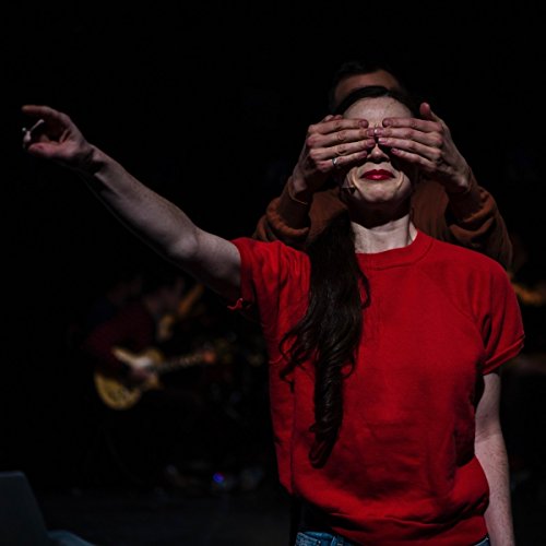 A person in a red shirt reaches out while another covers their eyes.