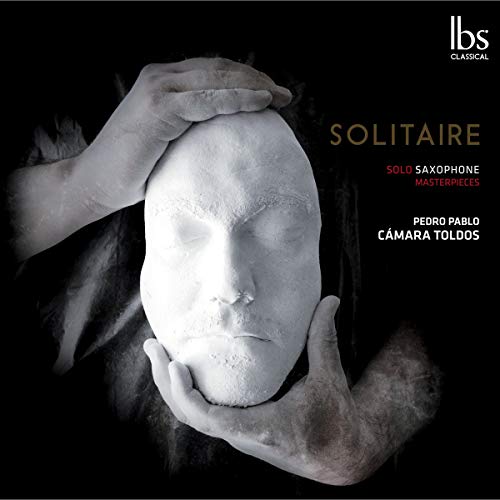 "CD cover with a plaster head being held by hands against a black background."