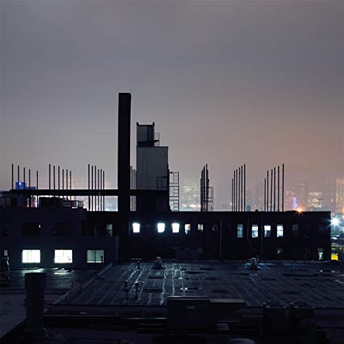 Rooftop view of industrial buildings against a dusky, city skyline.