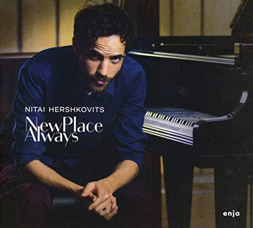 "Man sitting beside a piano, looking at the camera, with album title text."
