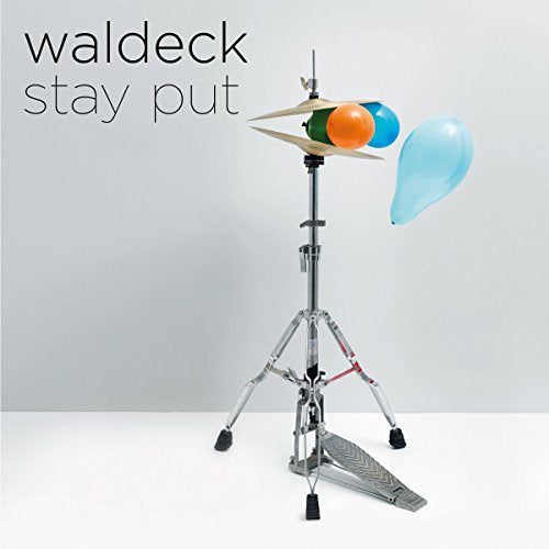 Silver drum stand with balloons and a paper plane attached, against a white background.