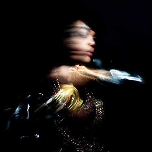 The image is a blurry photograph of a person. The alt text is: "Blurry image of a person in dark clothing against a black background."