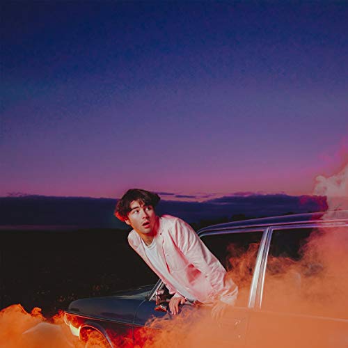 Young man leaning out of a car with orange smoke, purple sky.