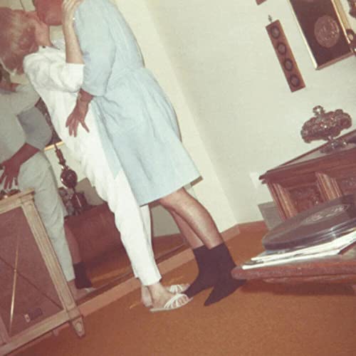 Vintage-toned photo of a couple embracing near records and furniture.
