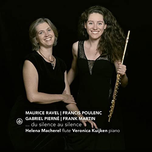 Two smiling women, one holding a flute, against a dark background.