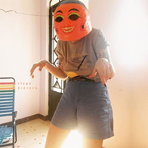 Person wearing an orange mask and blue shorts, album cover art.