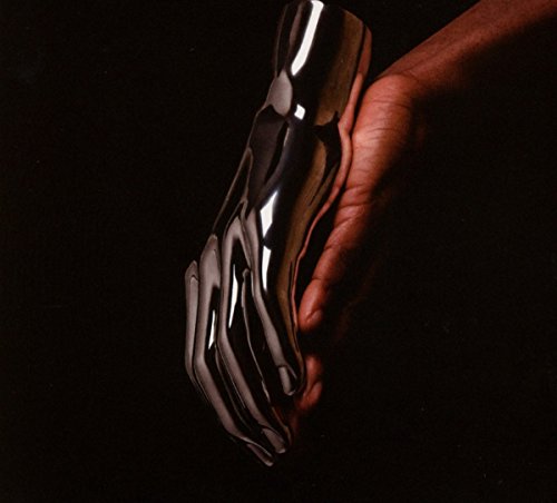 Hand-shaped, glossy black object held in a dark-skinned hand.