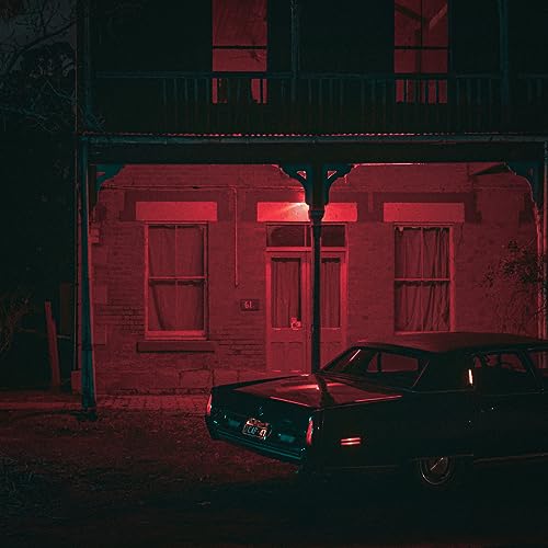 Red-lit building and vintage car at night, album cover art.