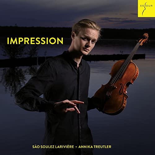 Violinist São Soulez Lariviere holding a violin by a calm lake.
