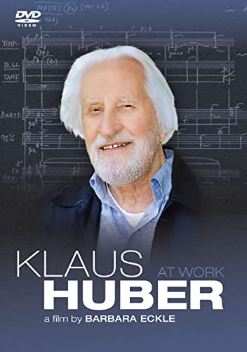 Portrait of Klaus Huber, a white-haired composer, with musical scores backdrop.