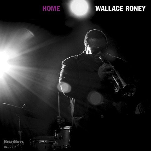 Black and white image of man playing trumpet on stage with spotlights.