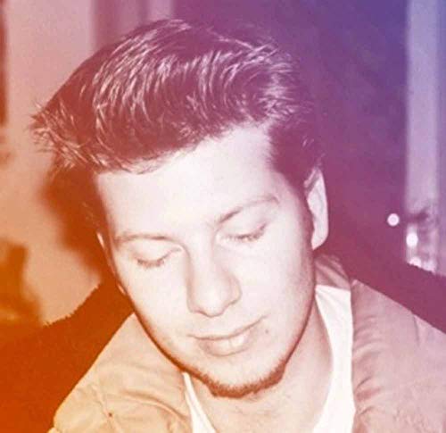 Close-up portrait of a young man with dark hair, eyes closed.
