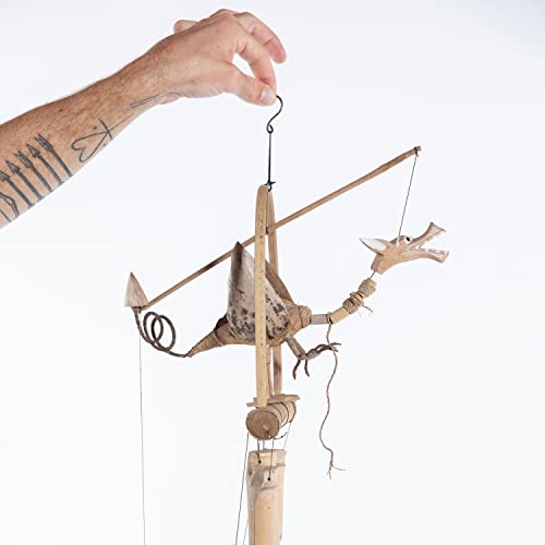 Hand holding a string attached to a wooden, articulated dragon puppet.
