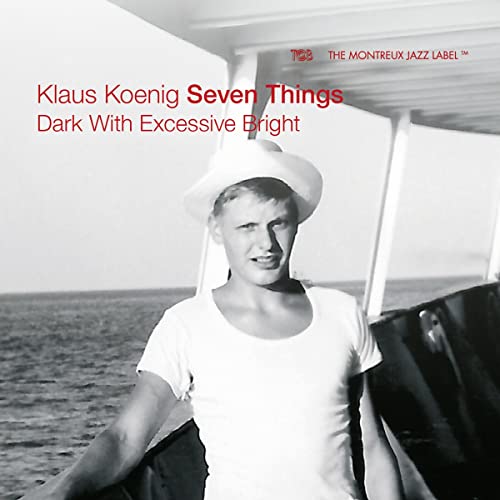 Black and white album cover featuring a man in a white hat by the sea.