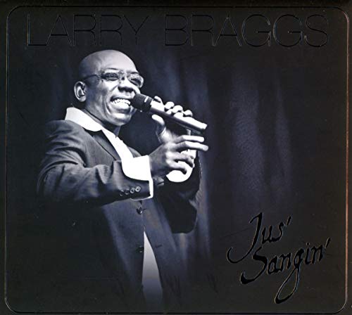 Black and white photo of Larry Braggs singing into a microphone on stage.