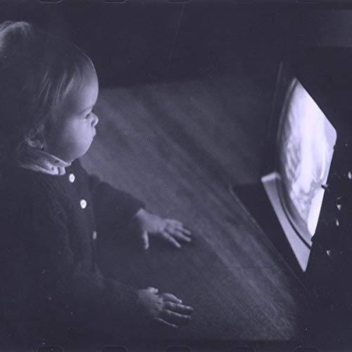 Black and white image of a child watching television on a wooden floor.
