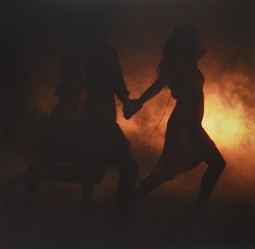 The alt text for the image is: "Silhouetted couple running hand in hand against a fiery orange background."