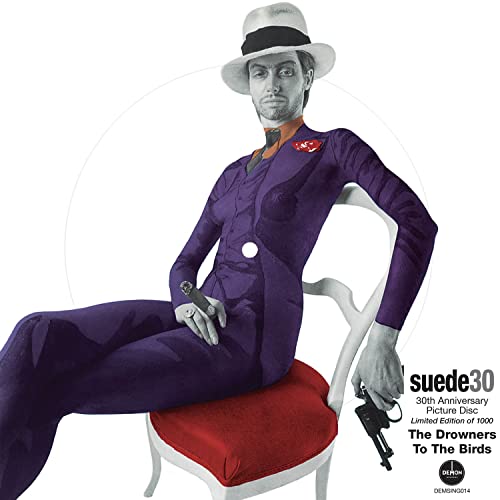Suede album cover: man in purple suit, holding a gun, seated.