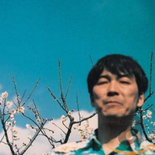 Close-up of a man with blossoming branches against a blue sky.