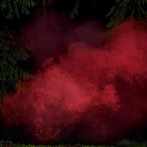 A red smoke cloud surrounded by green foliage against a dark background.
