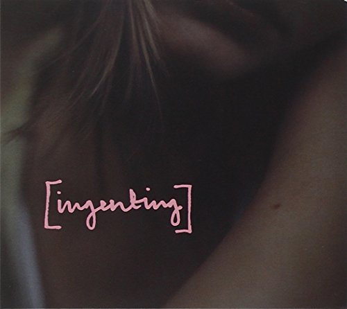 A dark album cover with a woman's back and pink text overlay.