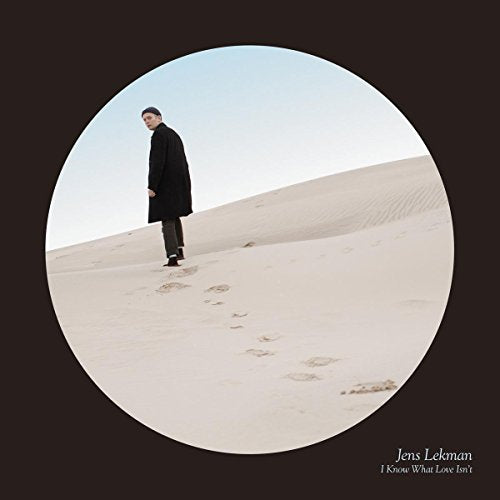 Jens Lekman album cover: man in black coat on sandy dunes.