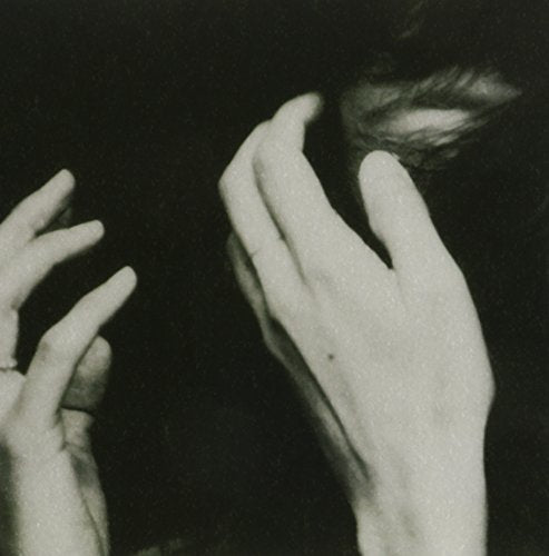 Black and white image of two hands reaching toward each other against a dark background.
