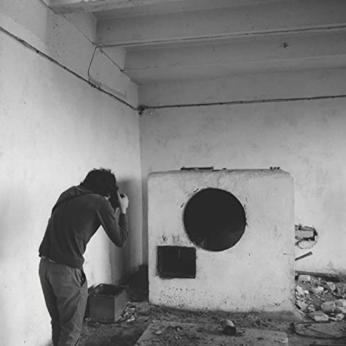 Black and white album cover featuring a person beside a brick oven.