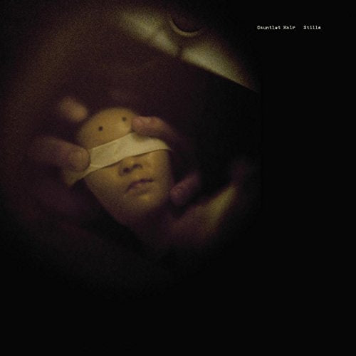 Dark, moody album cover featuring hands holding a doll with a blindfold.