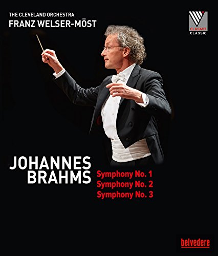 Conductor Franz Welser-Möst in a tuxedo, holding a baton, against a black background.