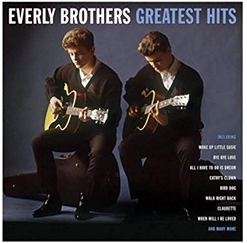 The Everly Brothers sitting on guitar cases playing acoustic guitars against a dark background.