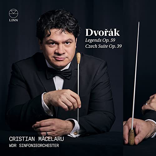 Conductor Cristian Macelaru in a tuxedo holding a baton against a dark background.