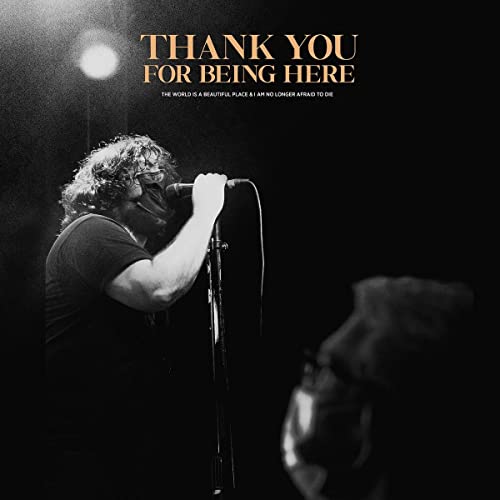 Black and white photo of a singer performing into a microphone onstage.