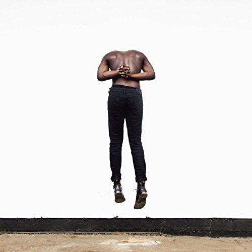 A shirtless man in black pants jumps against a white background.