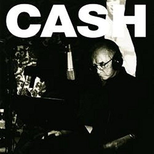Johnny Cash wearing headphones in a recording studio with the word CASH above him.