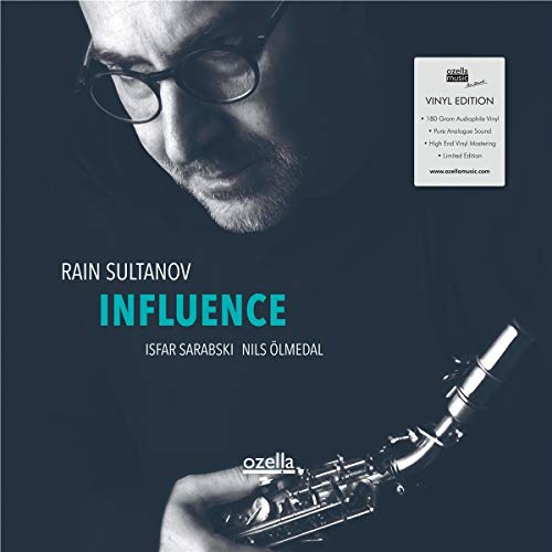 Man holding a saxophone, wearing glasses, on a dark blue album cover.