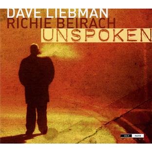 "Album cover with a man standing on a sidewalk, orange-toned image, artist names and title."