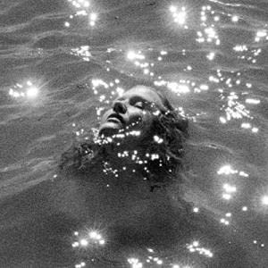 Black and white portrait of a person floating in water with sparkles.