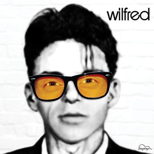 A man wearing sunglasses with orange lenses, with "wilfred" text in the top right corner.