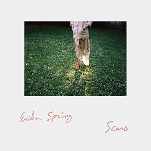 Woman in floral dress standing in green grass, album cover.