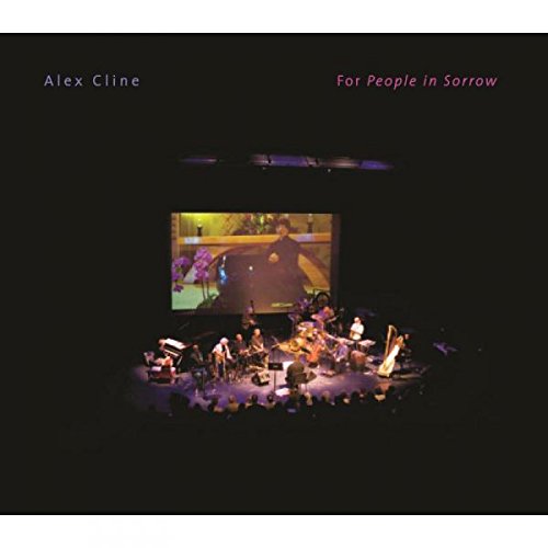 "Album cover featuring a band performing on stage with a large screen behind."