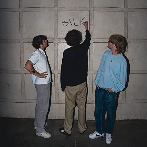 Album cover for Bilk featuring three people near graffiti.